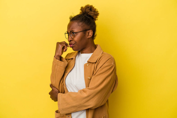 Young african american woman isolated on yellow background confused, feels doubtful and unsure. - Photo, Image