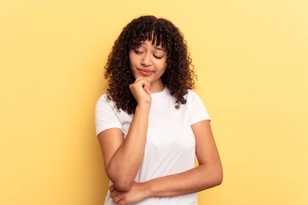 Young mixed race woman isolated on yellow background looking sideways with doubtful and skeptical expression. - Photo, Image