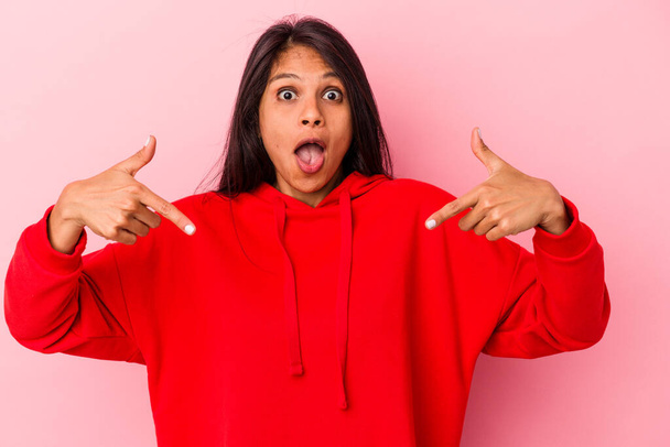 Young latin woman isolated on pink background points down with fingers, positive feeling. - Φωτογραφία, εικόνα