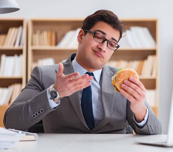 Hungry funny businessman eating junk food sandwich - Foto, imagen