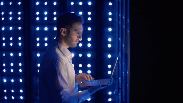 Ingénieur serveur masculin dans le centre de données. Ingénieur informatique inspectant une armoire de serveur sécurisée en utilisant la technologie moderne ordinateur portable coworking dans le centre de données. - Séquence, vidéo