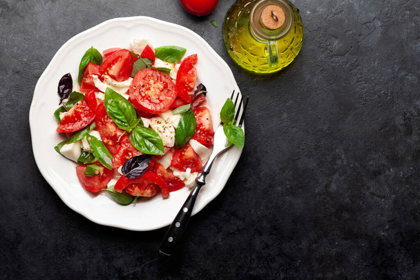 Caprese salad with fresh tomatoes, garden basil and mozzarella cheese. Top view flat lay with copy space - Foto, imagen
