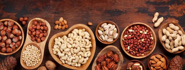 Verschiedene Nüsse Auswahl: Erdnüsse, Haselnüsse, Kastanien, Walnüsse, Pistazien und Pekannüsse auf Holztisch. Draufsicht flach gelegt - Foto, Bild
