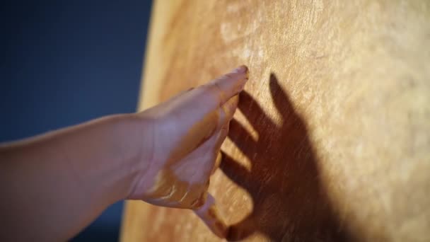 Silueta rukou talentované kreativní umělkyně pomalu pohybuje rukou v olejomalbě přes zlatou malbu, jako štětec. Tvorba grafu pro mistrovskou třídu v ateliéru umění. Prsty se jemně dotýkají plátna - Záběry, video