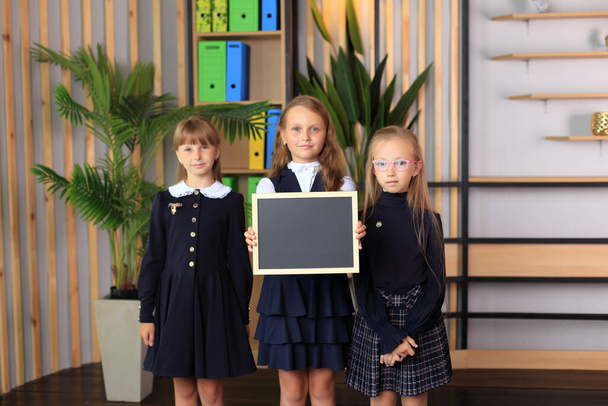 Három lány egy rajztáblát tart egy keretben.. - Fotó, kép