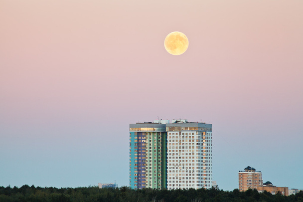 luna llena en el cielo rosa sobre casas urbanas
 - Foto, Imagen