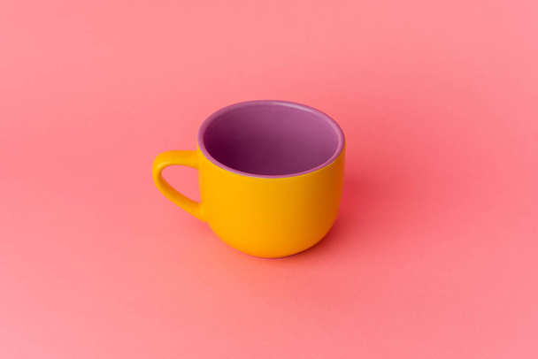 Жовта чашка ізольована на рожевому фоні
 - Фото, зображення