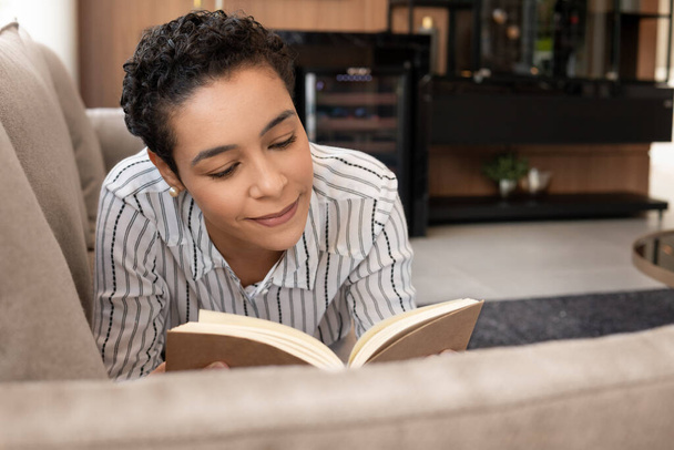 black woman reading book and enjoying weekend in the sofa - Photo, image