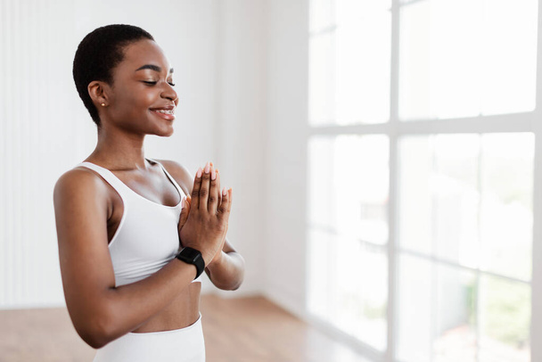 Zwarte vrouw mediteren in gebed pose met gesloten ogen - Foto, afbeelding