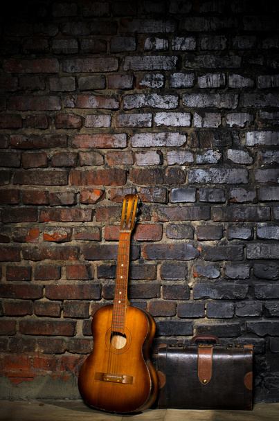 Гітара та ретро сумка на фоні цегляної стіни
 - Фото, зображення