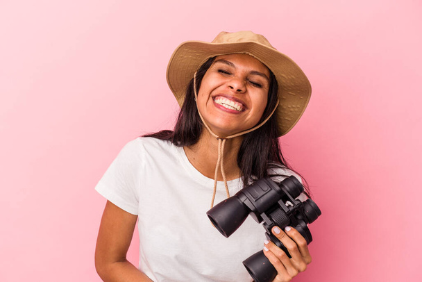 fiatal latin nő gazdaság távcső elszigetelt rózsaszín háttér nevetés és szórakozás. - Fotó, kép