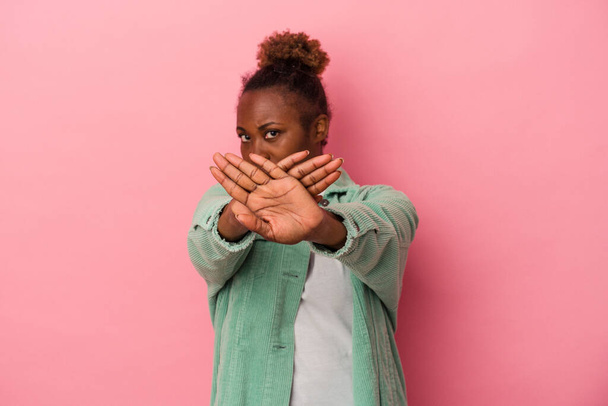 Nuori afrikkalainen amerikkalainen nainen eristetty vaaleanpunainen tausta seisoo ojennettu käsi osoittaa stop-merkki, estää sinua. - Valokuva, kuva