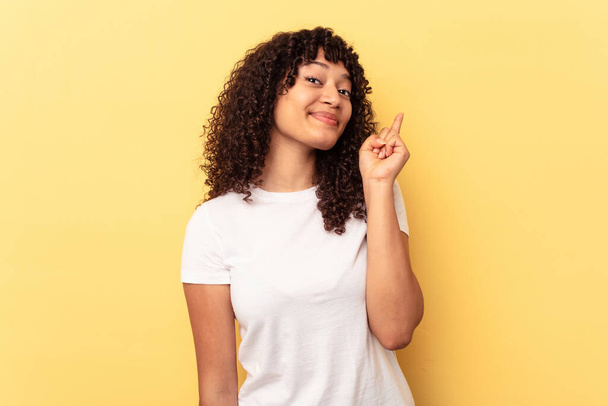 Young mixed race woman isolated on yellow background showing number one with finger. - Фото, зображення