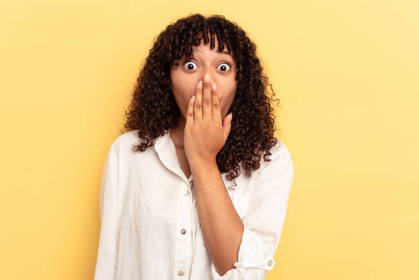 Young mixed race woman isolated on yellow background shocked, covering mouth with hands, anxious to discover something new. - Fotoğraf, Görsel