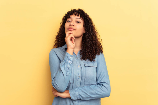Young mixed race woman isolated on yellow background suspicious, uncertain, examining you. - Foto, Imagen