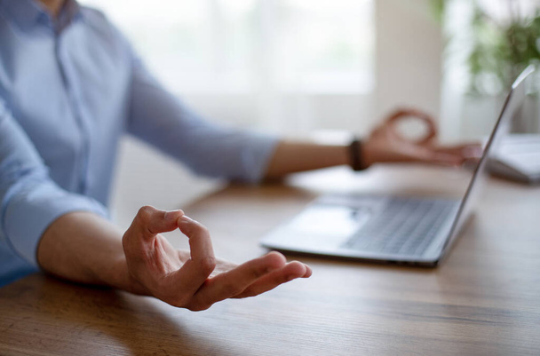 Closeup of Arab guy meditating in front of laptop, making gyan mudra, feeling peaceful, keeping calm at workplace - Photo, Image