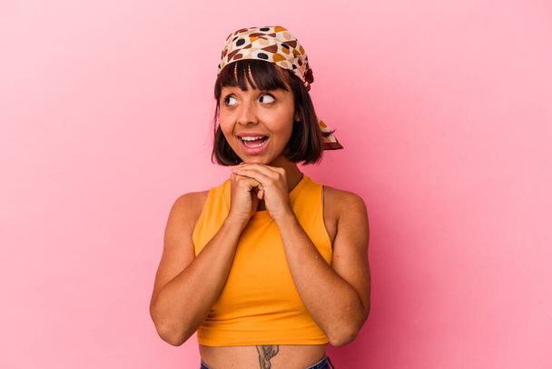 Young mixed race woman isolated on pink background keeps hands under chin, is looking happily aside. - Photo, Image