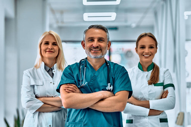 Smiling medical team with arms crossed in the hallway. Front view. Selective focus. - 写真・画像
