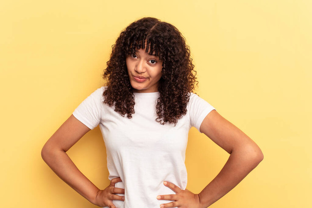 Young mixed race woman isolated on yellow background confused, feels doubtful and unsure. - Fotoğraf, Görsel