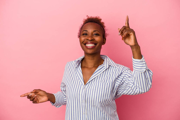 Jovem afro-americana isolada sobre fundo rosa apontando para diferentes espaços de cópia, escolhendo um deles, mostrando com o dedo. - Foto, Imagem
