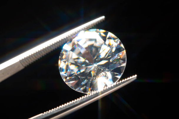Diamond in tweezers selective focus, inspection and analyzing of brilliant cut crystal polish quality. Jewellery professional hand making in the studio. Macro shot, shallow depth of view. - Photo, image
