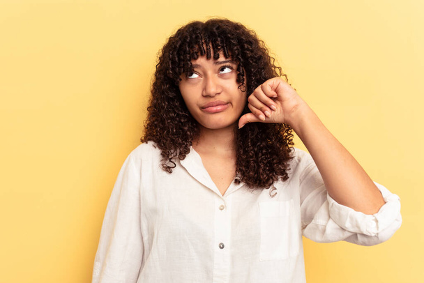 Young mixed race woman isolated on yellow background showing a dislike gesture, thumbs down. Disagreement concept. - Photo, Image