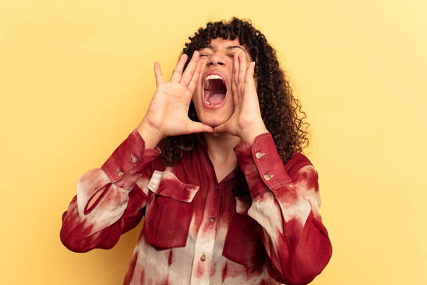 Young mixed race woman isolated on yellow background shouting excited to front. - 写真・画像