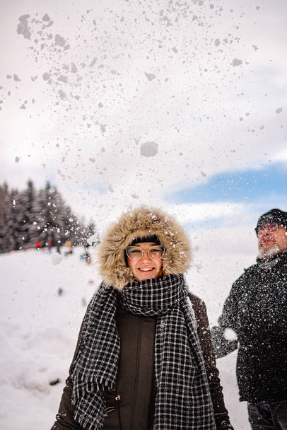 mladá žena baví ve sněhu s úsměvem, jak sníh je hodil na ni její otec; rekreační aktivní zimní koncept; - Fotografie, Obrázek
