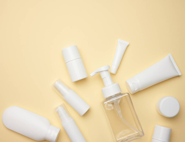 白いクリームチューブ、化粧品ディスペンサー、空の瓶とハンドクリーム、薄い黄色の背景に透明ディスペンサーのトップビュー。化粧品のブランディング,モックアップ - 写真・画像