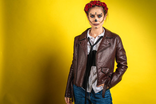 Portret Kalaveri Katriny z bliska w białej koszuli i brązowej skórzanej kurtce na żółtym tle, wygląda prosto. Dia-de -los -muertos. Dzień śmierci. Halloween - Zdjęcie, obraz