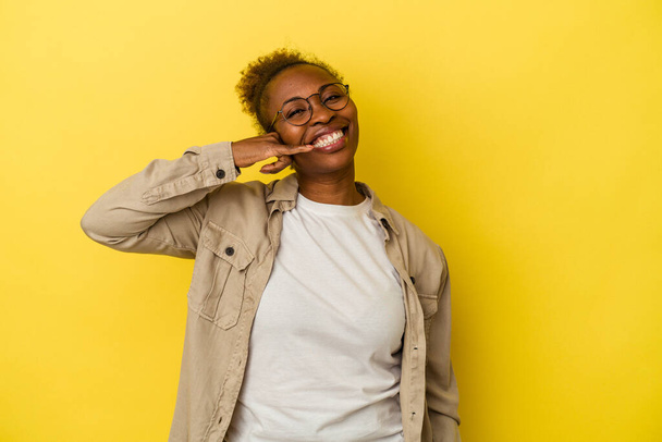 Giovane donna afroamericana isolata su sfondo giallo mostrando un gesto di chiamata cellulare con le dita. - Foto, immagini