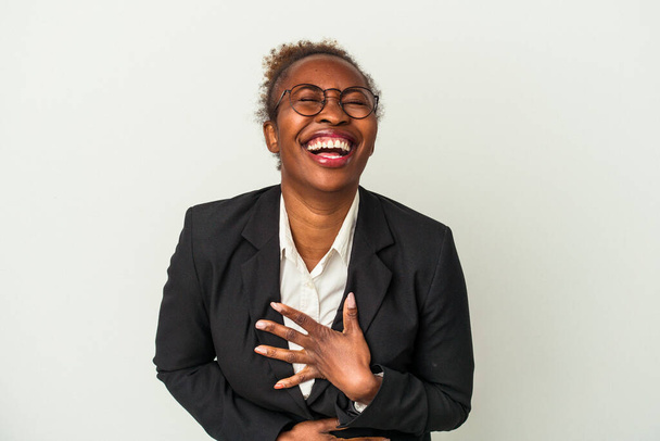 白い背景に孤立した若いビジネスアフリカ系アメリカ人女性が喜んで笑い、胃の上に手を保つ楽しみを持って. - 写真・画像