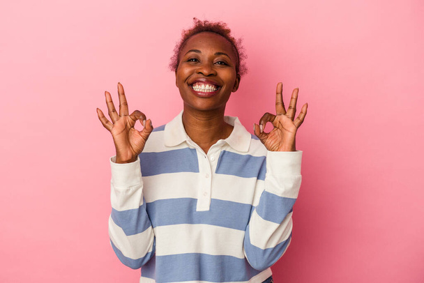 Young african american woman isolated on pink background cheerful and confident showing ok gesture. - Foto, imagen