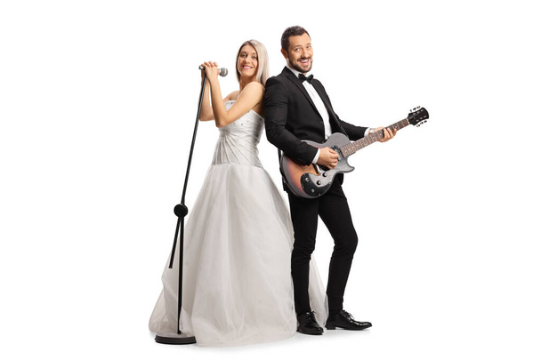 Full length shot of a bride and groom with a guitar and a microphone isolated on white background - Foto, Imagem