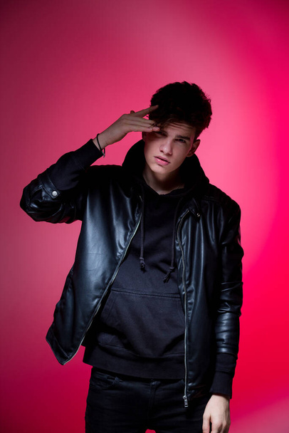 Cute brutal man in black leather jacket model style. Portrait of a handsome guy on pink studio background. Man In Black Jacket. Young Fashion Man In Leather Jacket on a pink background. - Photo, Image