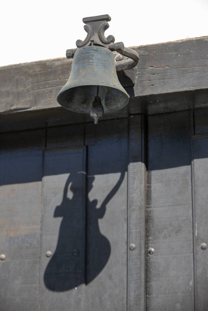 Una campana de hierro colgando de la puerta vieja - Foto, imagen