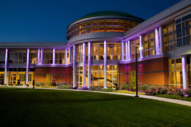 Porte d'entrée du bâtiment moderne avec de nombreuses fenêtres au crépuscule éclairé violet - Photo, image