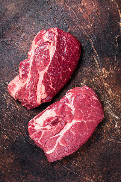Raw Chuck eye roll beef steak on butcher table. Dark background. Top view - Foto, Imagen