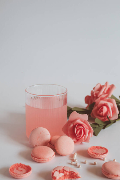 Pink macaron cookies and rose flowers on white background. French cookie. Soft pastel vintage tone.  - Foto, Bild
