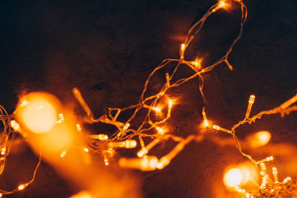 Warm light illuminated garland close up on dark background - Foto, imagen
