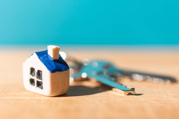Miniatyyri uusi talo talon avaimet puinen sininen hämärtynyt tausta, kiinteistöjen ja omaisuuden liiketoimintakonsepti.. - Valokuva, kuva