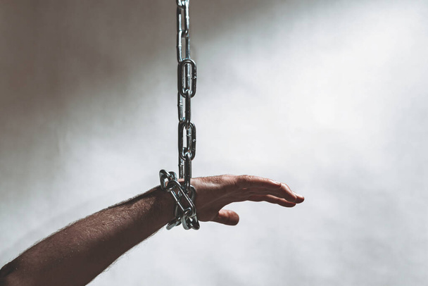 Hand with chain hang,chain in hand,the chain wound on the hand,gray background.Copy space. - Photo, Image