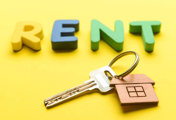 Word RENT met sleutel van huis op gele achtergrond, close-up - Foto, afbeelding