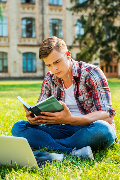 Student reading book on the grass - Фото, зображення