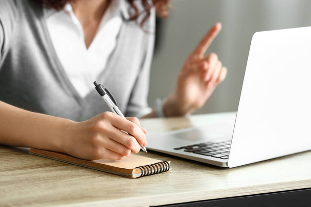 Молода жінка пише нотатки під час онлайн-інтерв'ю на роботі вдома
 - Фото, зображення