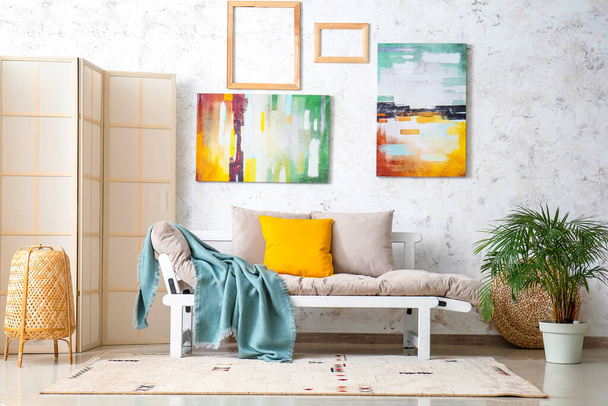 Εσωτερικό κομψό σαλόνι με καναπέ, πτυσσόμενη οθόνη και πίνακες ζωγραφικής - Φωτογραφία, εικόνα