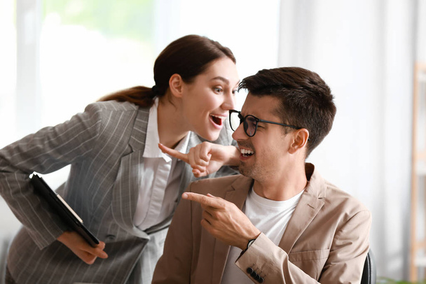 Young woman sharing gossip with her colleague in office - Foto, Imagem