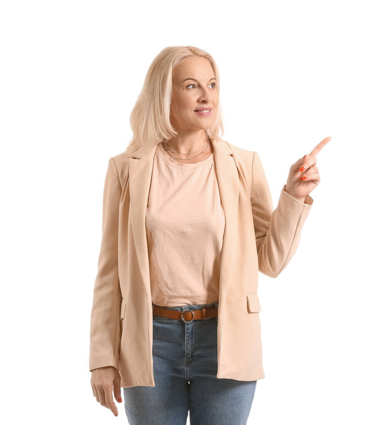 Beautiful mature woman pointing at something on white background - Photo, image