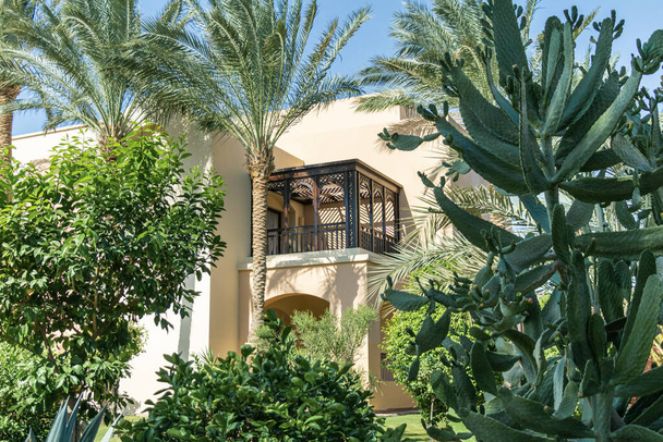Brązowy drewniany balkon z łukami na budynku w środku tropikalnego ogrodu - Zdjęcie, obraz