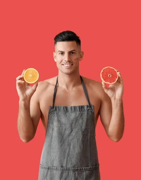 Young man with orange and grapefruit on color background. Vegan Day - Photo, Image